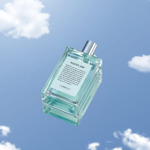 Sticlă parfum bărbătesc #Lucky_Day cu lichid verde-albăstrui și capac metalic argintiu pe fundal cer senin.