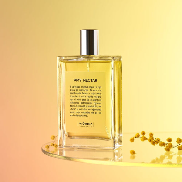 Parfum femei #My_Nectar, sticlă transparentă cu etichetă galbenă, capac argintiu, fundal gradient cald.