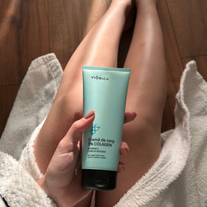 Cremă de corp Viorica cu 5% colagen, tub albastru mat, capac negru, suprafață lemnoasă și halat alb.