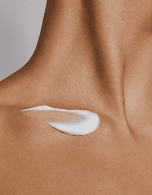 Cremă albă hrănitoare aplicată pe piele netedă, oferind o hidratare intensă și un aspect catifelat.