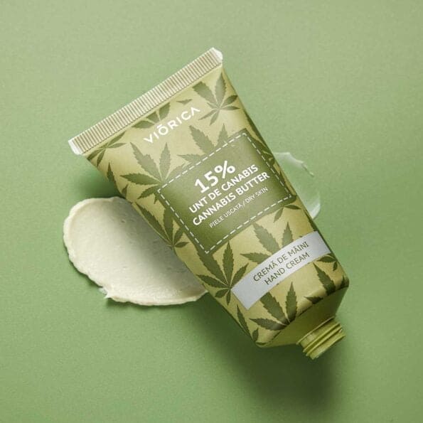 Cremă de mâini Viorica cu 15% unt de canabis, ambalaj verde cu detalii frunză și textură cremoasă.