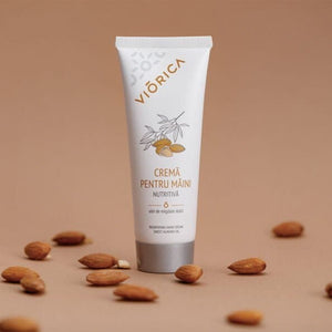 Cremă nutritivă pentru mâini Viorica, tub alb cu capac argintiu, ilustrată cu migdale pe fundal maro.