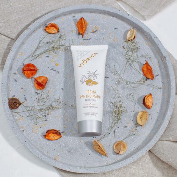 Cremă nutritivă pentru mâini Viorica pe fundal gri, ornamente vegetale portocalii și bej.