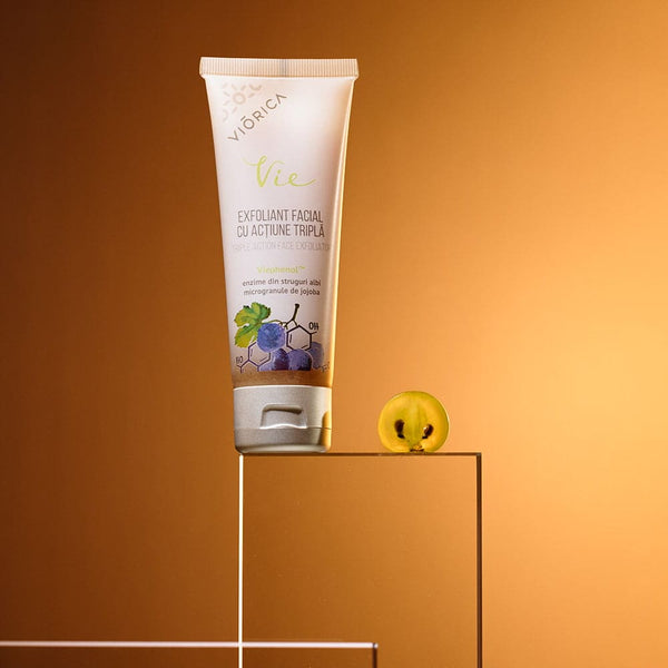 Exfoliant facial Viorica Vie cu enzime de struguri albi și microgranule de jojoba pe fundal auriu.