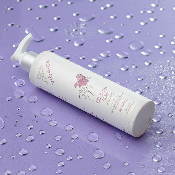 Sticlă albă Viorica Sensivio pe fundal lila cu picături, design floral delicat.