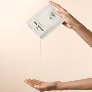 Plic masca de față cu colagen 21Collagen, lichid seros curge, mâini feminine, fundal bej.