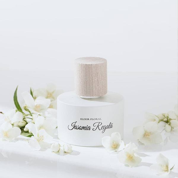Parfum floral cu note de iasomie, capac din lemn natural, detalii elegante albe.