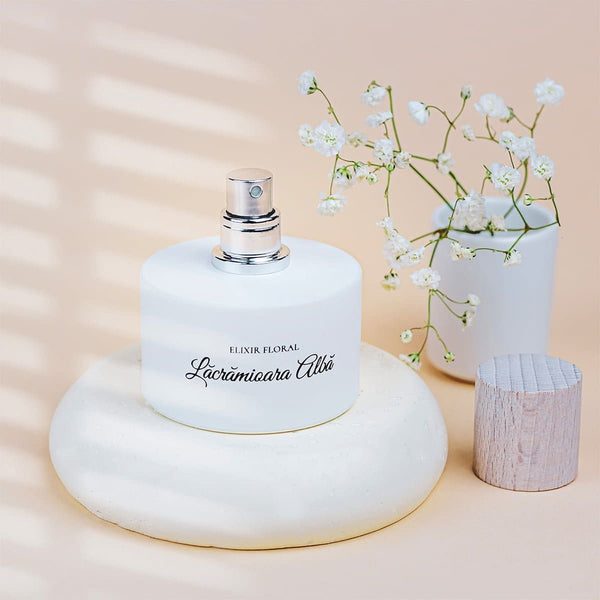 Parfum Elixir Floral Lăcrămioara Albă, sticlă albă cu capac argintiu, decor floral.
