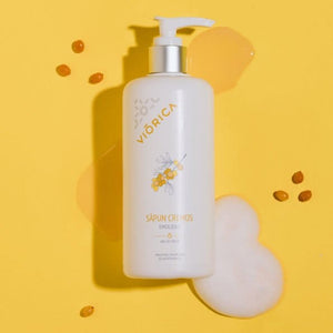 Sticlă albă cu pompă a săpunului cremă emolient Viorica, decorativă cu flori galbene și fundal galben.