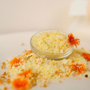 Sare de baie cu mușețel și gălbenele, textură granulată, nuanțe galbene și portocalii.