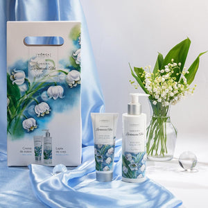 Set pentru corp „Elixir Floral Lăcrămioara Albă”, ambalaj elegant pe fundal albastru satinat, flori în vas.