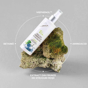 Spray termoprotecție 230°C Viorica Vie, sticlă albă, detalii ingrediente naturale, pe piatră cu mușchi.