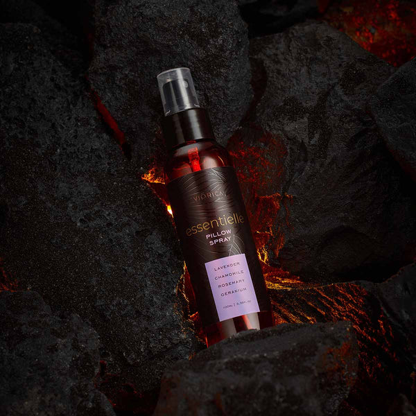 Spray perne Viorica Essentielle, flacon maro, detalii așezate pe fundal texturat negru.